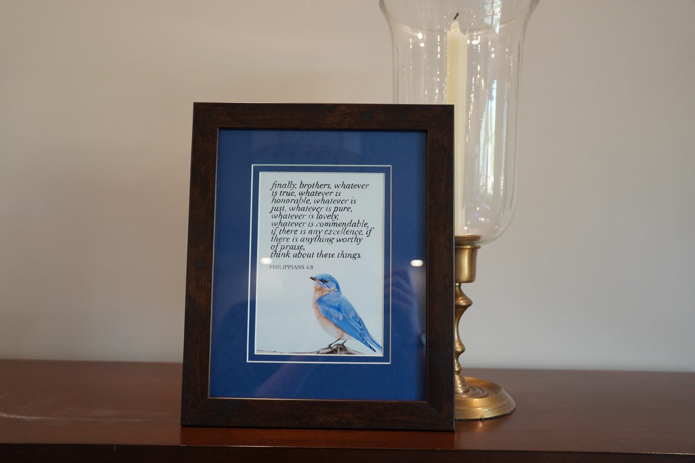 Framed calligraphy print of a bluebird with Philippians 4:8, on a dark wood frame