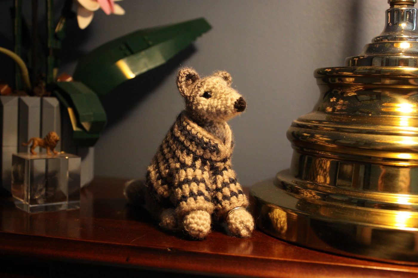 Raphaela, a crochet wolf in a striped sweater, on a mantelpiece