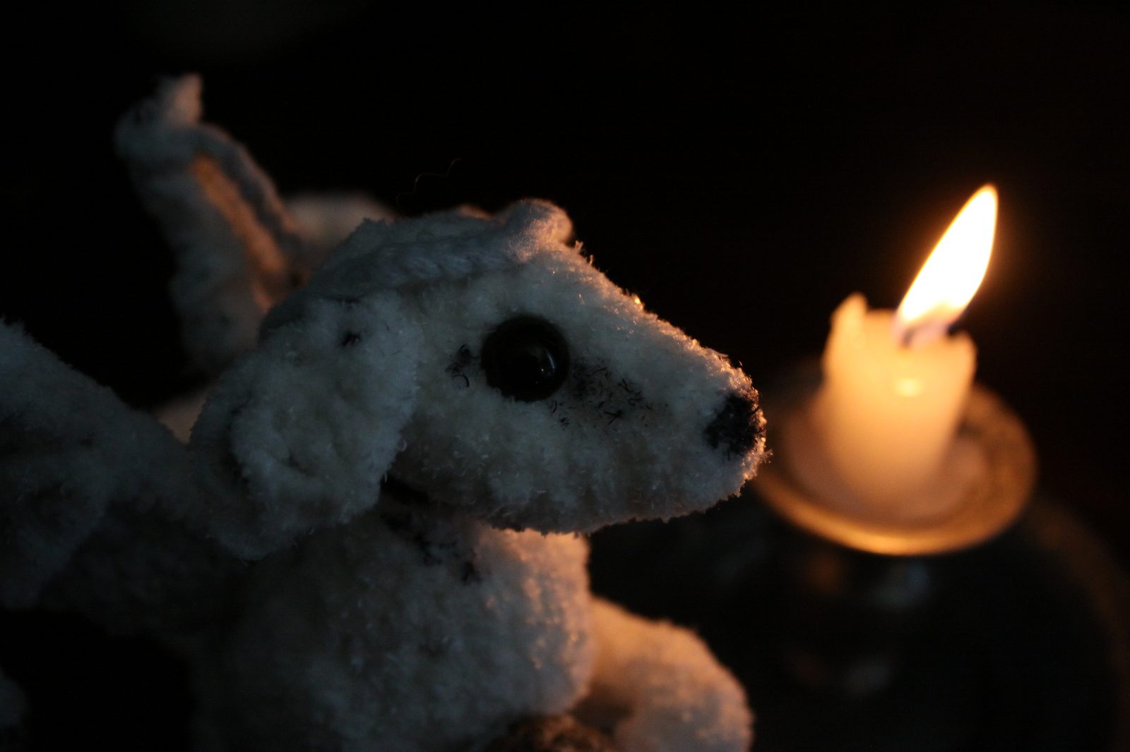 A recently finished white crochet creature, lit by candlelight